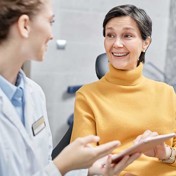 A dental implant patient talks to her surgeon